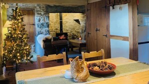 A cozy dining area with a wooden table, two chairs, a Christmas tree, and a fireplace. - Secluded Mountain Stay - Stunning Views of Eryri (Dolgellau)