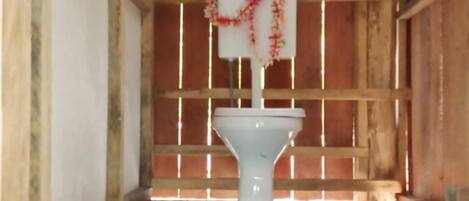 Un baño con inodoro, suelo de baldosas y paredes de madera.