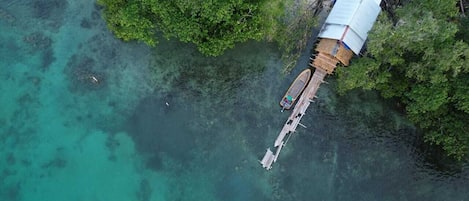 An aerial view of a small island with a single wooden boat docked near a small structure with a blue roof.