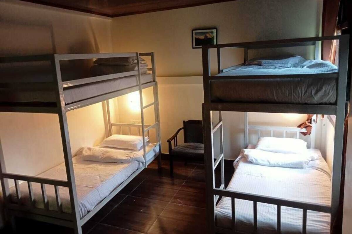 Habitación con literas, dos literas, una silla pequeña y un cuadro en la pared.