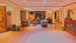 Un vestíbulo espacioso con techo alto, una zona de estar con sofás y una mesa de centro, y un mostrador de recepción.