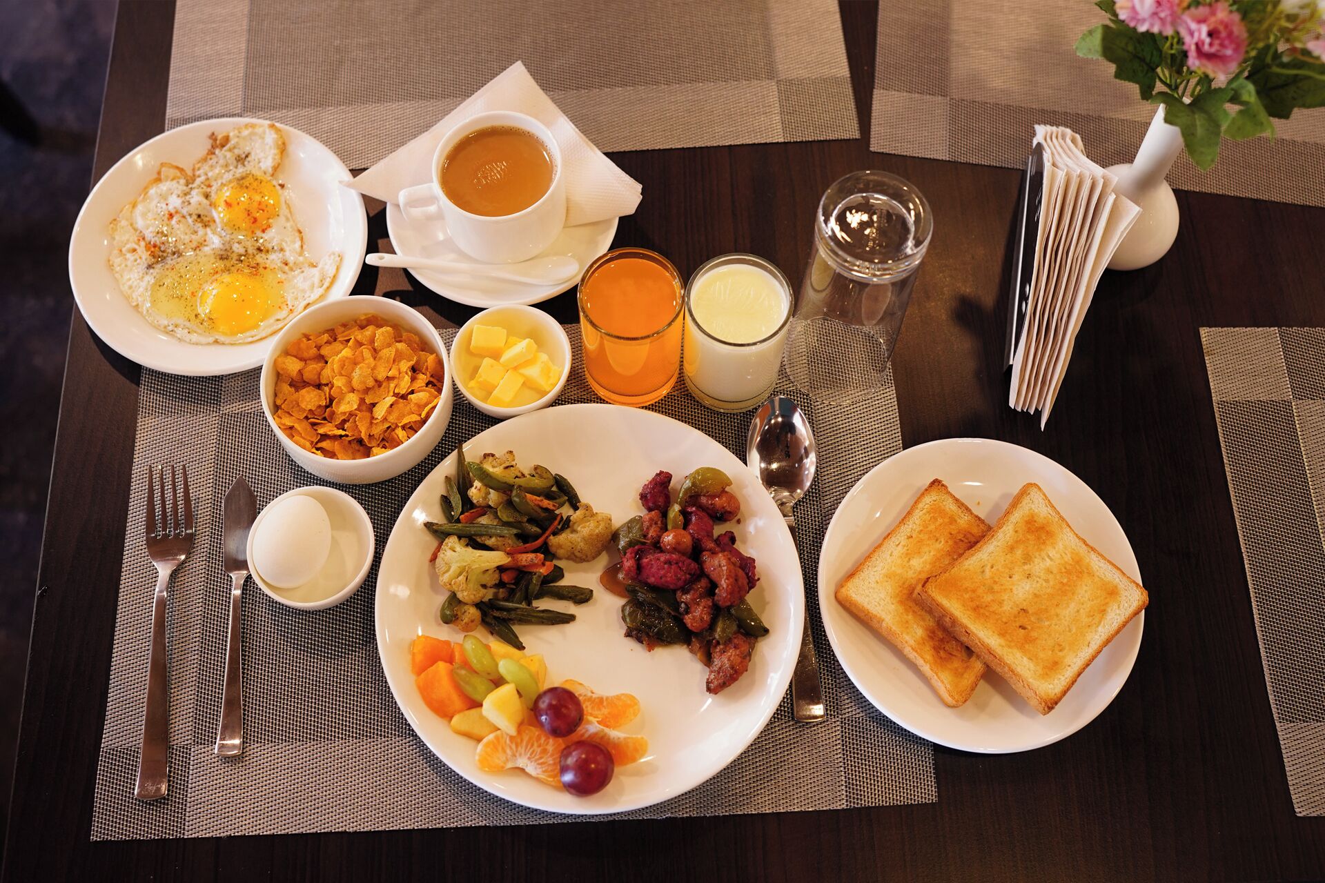 Ein gedeckter Frühstückstisch mit Eiern, Toast, Obst und einer Kaffeetasse.