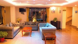 Un salón luminoso con dos sofás, una mesa de centro y un televisor montado en la pared.