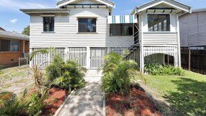 A two-story house with a front porch, a fenced yard, and a pathway leading to the entrance. - Wellington House (Mackay)