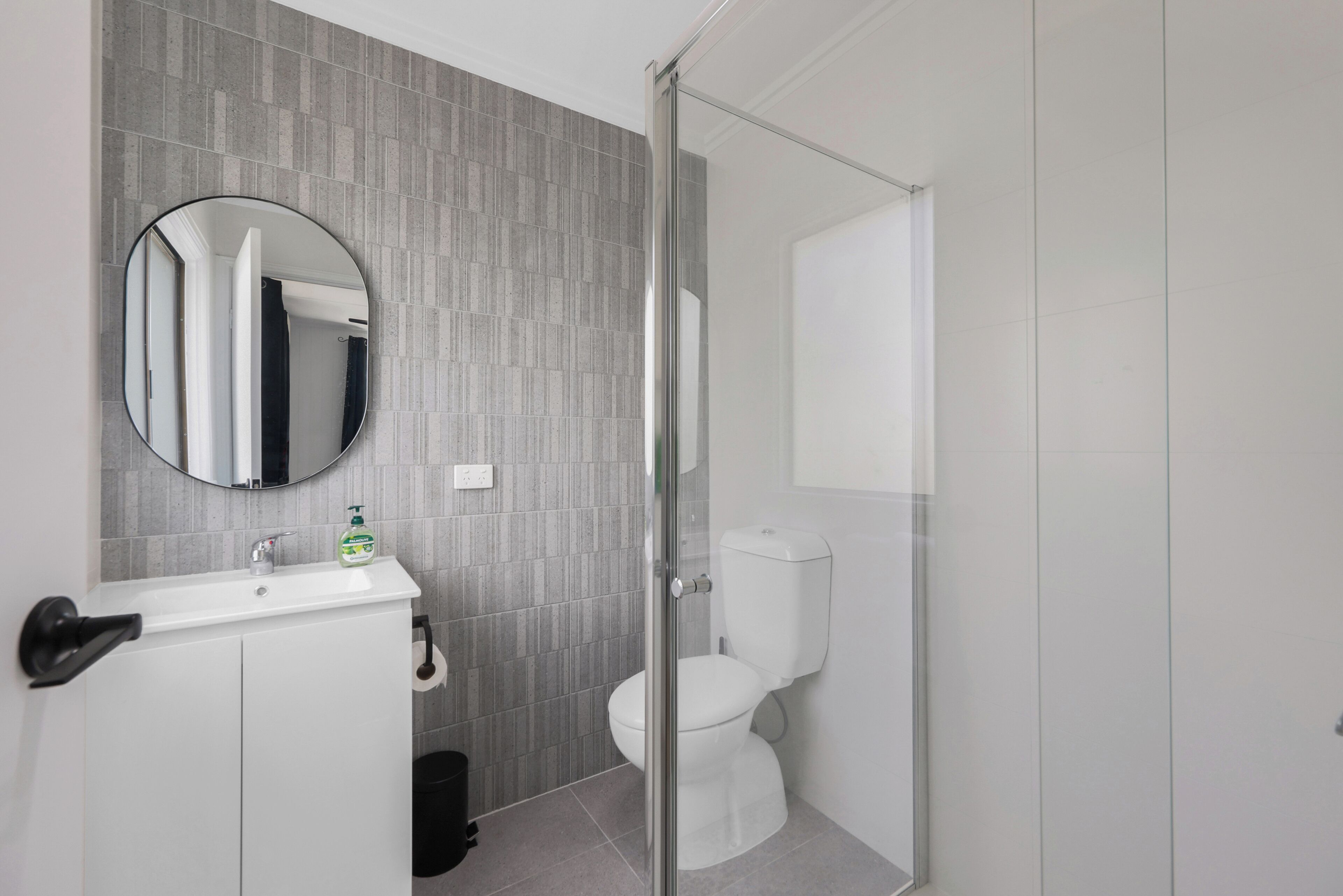 A modern bathroom with a white sink, mirror, and toilet.
