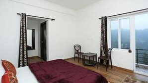 Un dormitorio con cama, una mesita, dos sillas y un balcón con vistas.