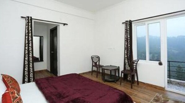 Een slaapkamer met een bed, een tafeltje, twee stoelen en een balkon met uitzicht.
