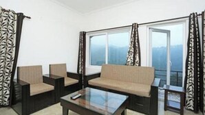 Una habitación moderna con sofá, dos sillones, una mesita de centro y ventanas amplias con cortinas.