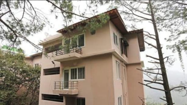 Un edificio de varios pisos con balcones, rodeado de árboles.