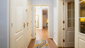 Un pasillo con puertas blancas, una alfombra de diseño geométrico y piso de madera.