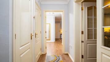 A hallway with white doors, a carpet with a geometric pattern, and a wooden floor.