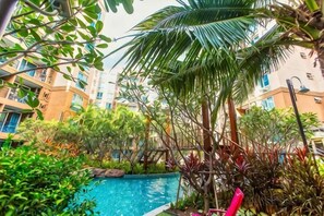 Una piscina rodeada de exuberante vegetación y edificios de varios pisos.