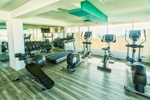 Un gimnasio con equipo de ejercicio, una banca y un espejo grande.