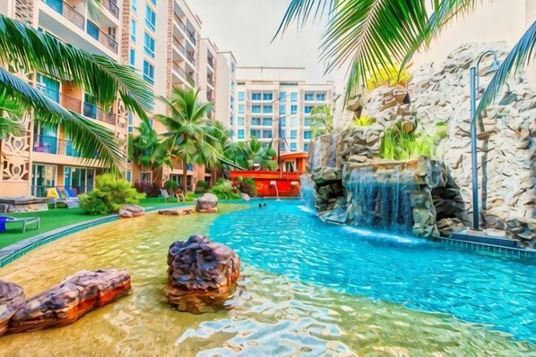 Una piscina con cascada, rodeada de palmeras y un edificio de varios pisos.