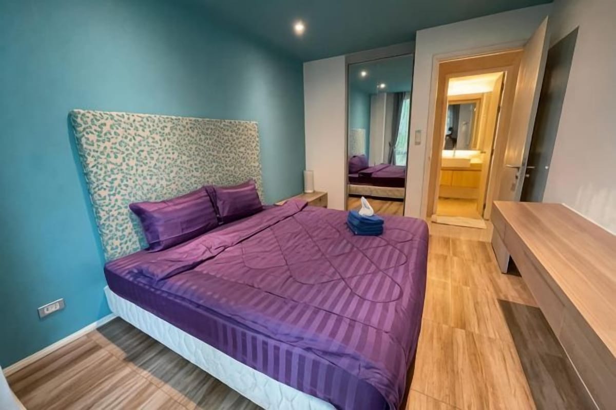 Un dormitorio con cama, cabecero de madera, mesitas de noche y un espejo.