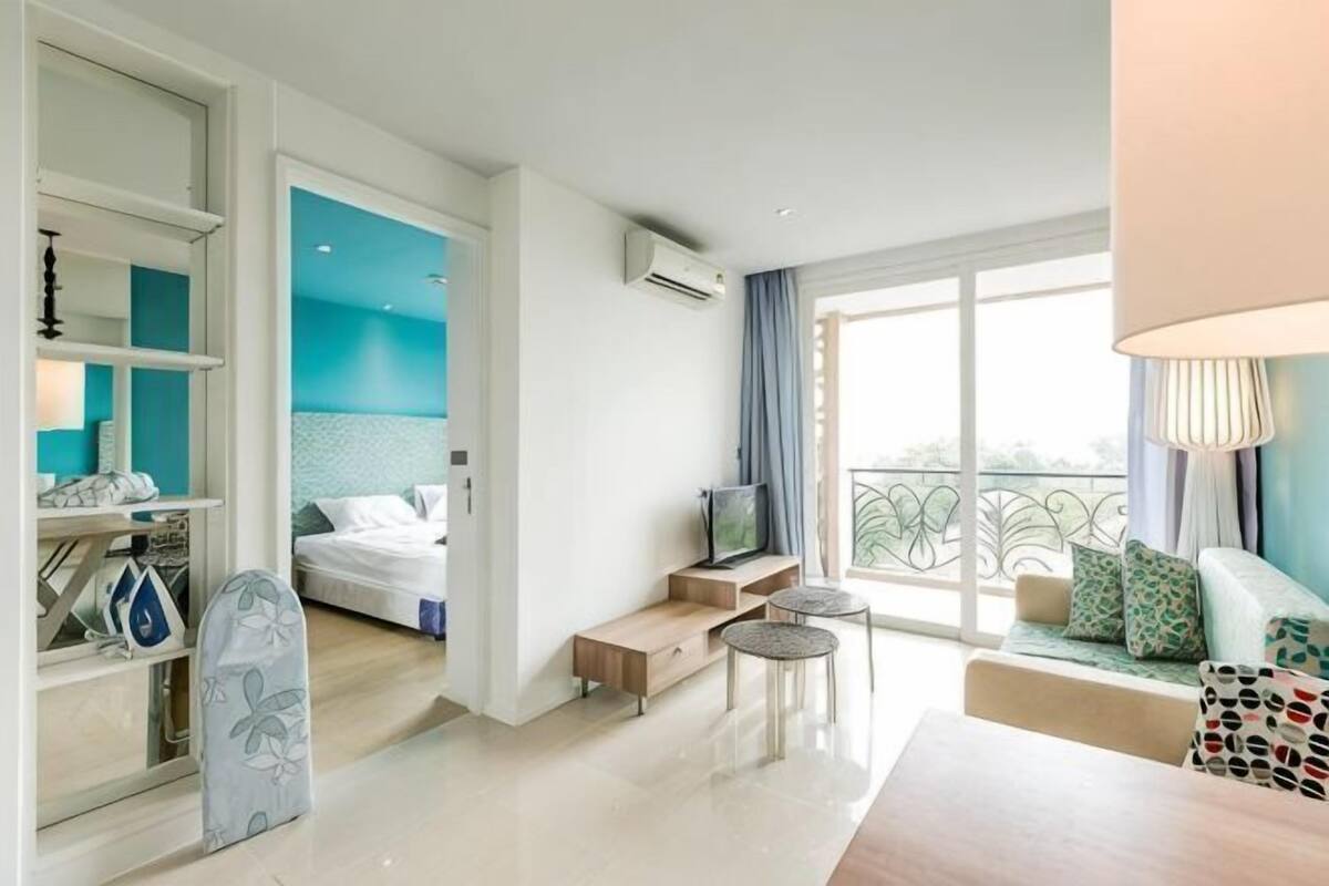 Een moderne hotelkamer met een bed, een televisie, een balkon, een zithoek en een klein tafeltje.