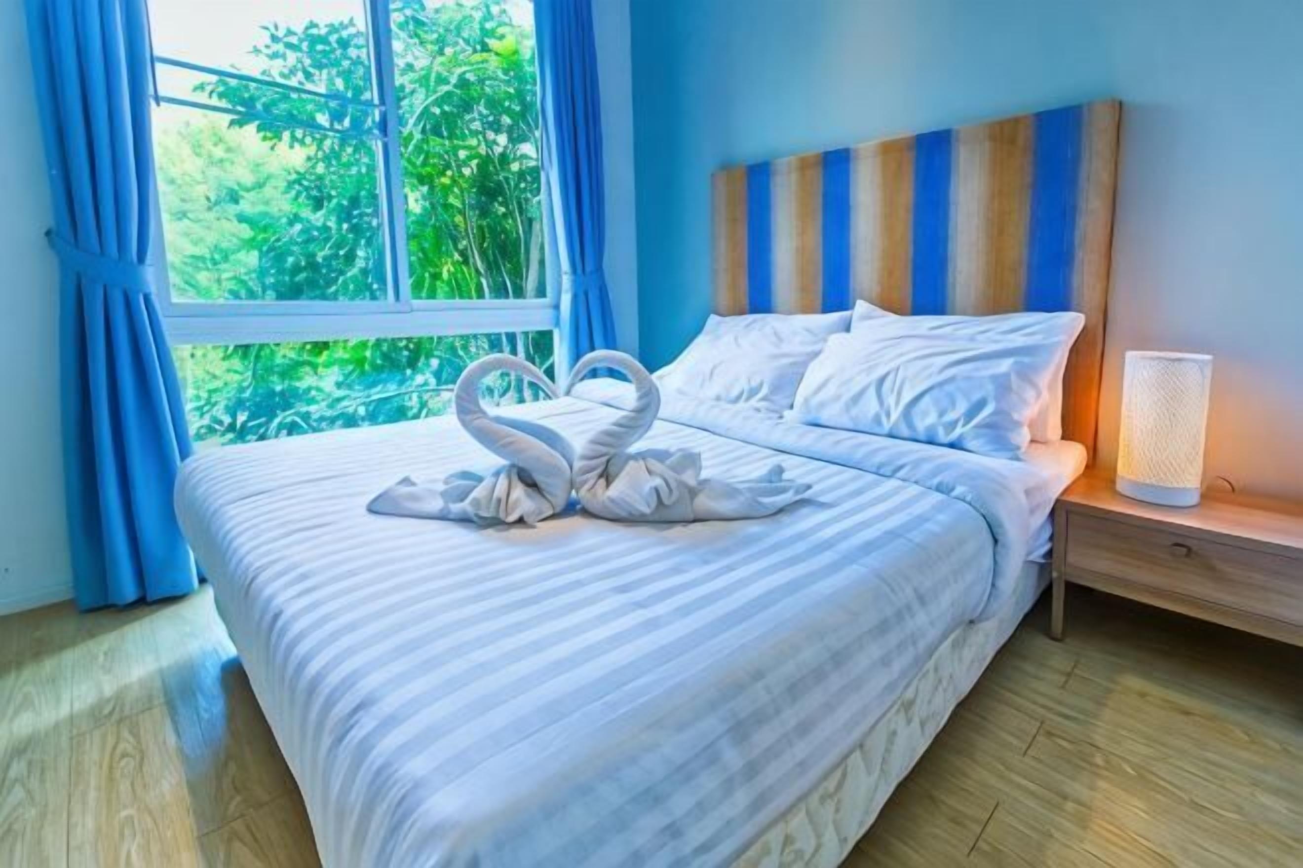 A hotel room with a bed, a nightstand, a lamp, and a window with curtains.