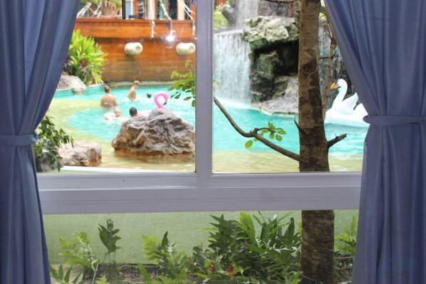 A view through a window of a pool area with a waterfall and a swan decoration. - Atlantis Condo Resort Jomtien TLH (Pattaya)