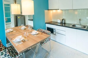 A modern kitchen with a dining table set for four, a sink, and a refrigerator. - Atlantis Condo Resort Jomtien TLH (Pattaya)
