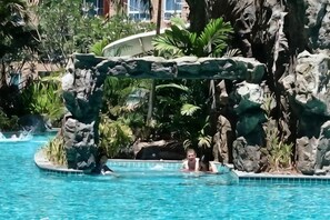 En pool med ett vattenfall som rinner nerför en klippvägg, och en person i vattnet.