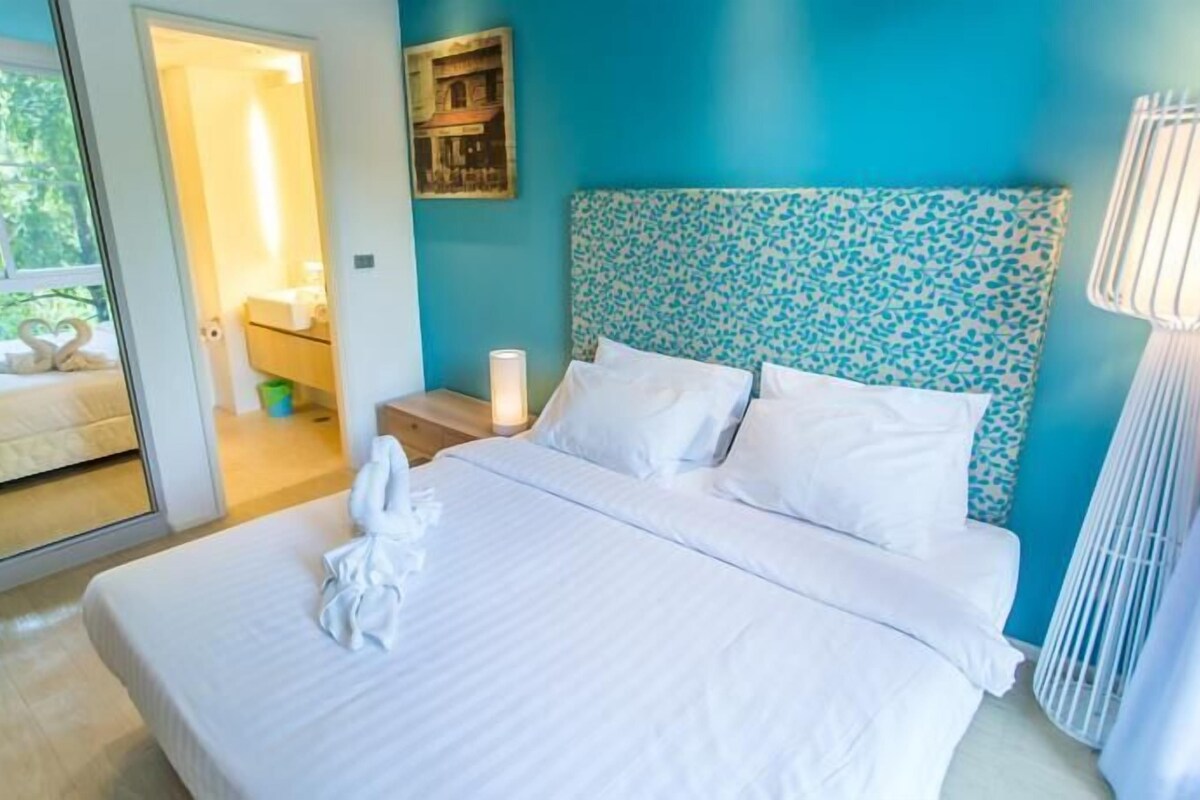 Une chambre à coucher comprenant un lit, une table de chevet, une lampe, un miroir et une vue sur l’extérieur.