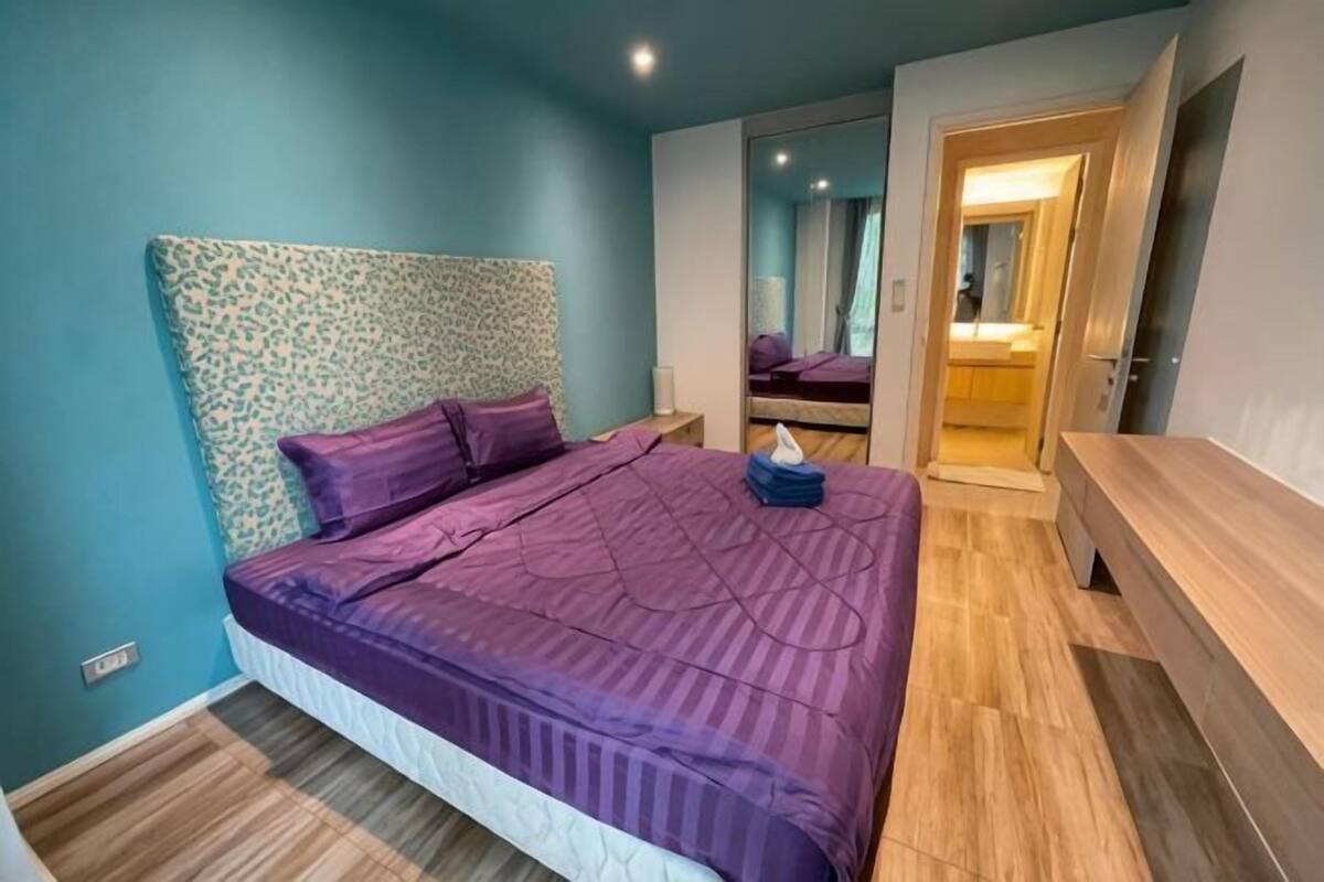 Een slaapkamer met een bed, een houten hoofdbord, nachtkastjes en een spiegel.
