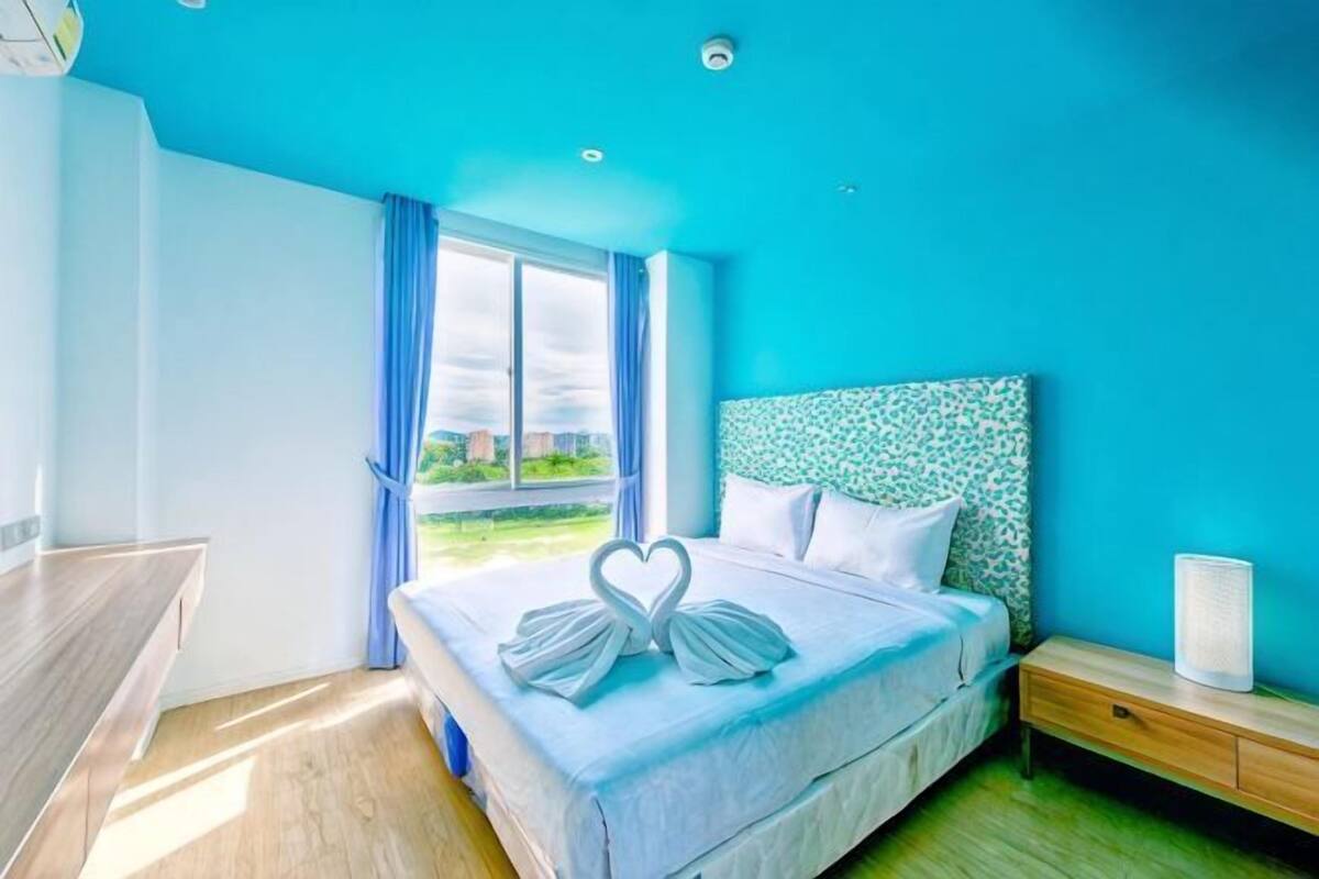 Een hotelkamer met een bed, nachtkastje en een raam met gordijnen.