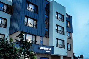 A multi-story building with balconies, a visible entrance, and signage. - The Naeun Stay (Seogwipo)