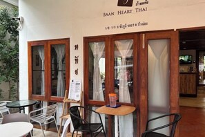 A restaurant interior with tables and chairs, a menu board, and a sign above the entrance. - Baan Heart Thai (Chiang Mai)