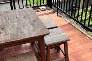 Una mesa y banco de madera en un patio con suelo de baldosas y barandilla de metal negro.