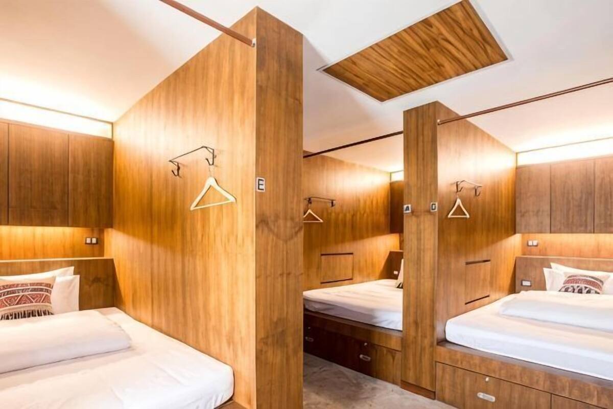 A room with wooden paneling, two beds, bedside tables, and wall-mounted light fixtures.