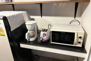 A kitchenette with a microwave, toaster, and coffee maker on a black countertop. - Baan Heart Thai (Chiang Mai)