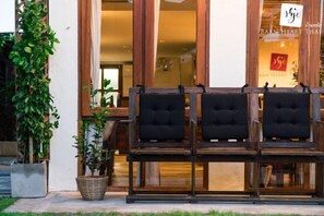 Un banco de madera con cojines negros frente a un edificio con un letrero que dice "BAAN HEART THAI".