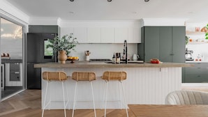 Une cuisine moderne avec un îlot central, des meubles blancs et des tabourets de bar.
