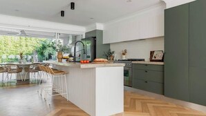 Une cuisine moderne dotée d’un îlot central, de tabourets de bar et offrant une vue sur la verdure environnante.