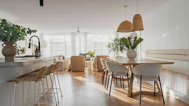 Une cuisine moderne dotée d’un îlot central, de tabourets de bar et d’un coin repas avec des chaises.