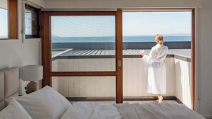 Un dormitorio con un amplio ventanal que da a un balcón con vistas al mar.