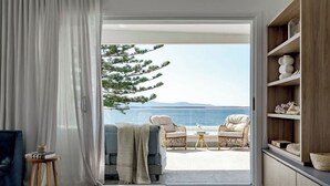 An open living space with a view of the sea, a sofa, a coffee table, and a bookshelf.