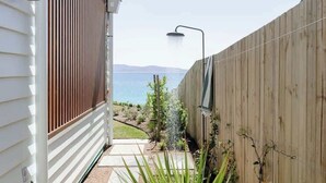 A narrow pathway leading to a wooden fence with a view of the sea.