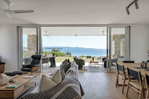 Un salon moderne doté d’une grande porte vitrée donnant sur un balcon avec vue sur la mer.