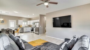 Ein modernes Wohnzimmer mit einer Couch, einem Couchtisch und einem an der Wand befestigten Fernseher.
