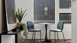 Una habitación moderna con un ventanal grande, dos sillas, una mesita y una planta en maceta.