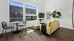 Una sala de estar moderna con un sofá, dos sillones, una mesita redonda, un televisor y un ventanal grande.