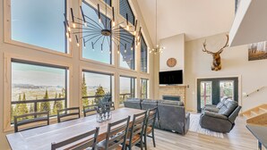 A spacious living area with a dining table, sofa, and a mounted deer head. - Views, Trails, Hot Tub & More: Luxe Wyoming Oasis (Dubois)
