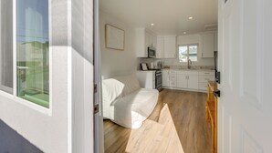 A modern kitchen with white cabinets, a microwave, and a wooden dining table. - 35 Mi to LA: Modern Apartment in Chino! (Chino)