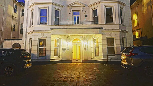A corner building with a prominent entrance, multiple windows, and a balcony. - LUXURY 2 BED APARTMENT BY THE SEA (Bournemouth)