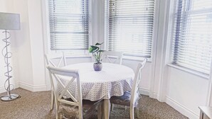 A dining area with a round table, white chairs, and a potted plant. - LUXURY 2 BED APARTMENT BY THE SEA (Bournemouth)