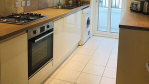 A modern kitchen with a gas stove, oven, and dishwasher. There is a window with a view of the outside. - LUXURY 2 BED APARTMENT BY THE SEA (Bournemouth)