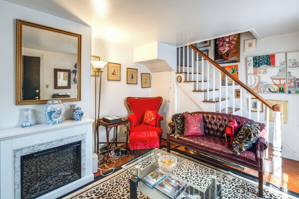 A living room with a fireplace, a red armchair, a leather sofa, and a staircase with a railing. - 1 Mi to Old Town: Historic Area Gem in Alexandria (Alexandria)