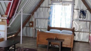 A loft bedroom with a sloped ceiling, a wooden bed, a desk, and a window with curtains. - Kinglayang Homestay (Kalimpong)